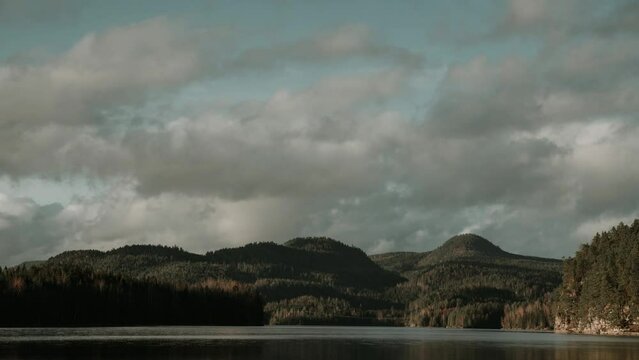Time lapse video of moving clouds over forest lake in Southern Norway