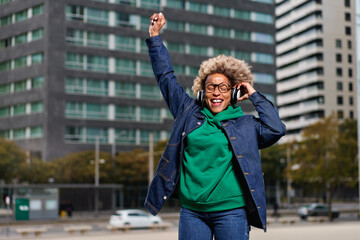 African American woman with afro hairstyle smiling in urban background. Black girl wearing casual clothes.