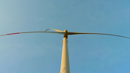 Wind turbine in an offshore wind farm in the green field against low sun on sunrise the close-up.