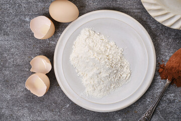 Muffin, baking ingredients: Flour, shell of broken eggs, cocoa in spoon on the table