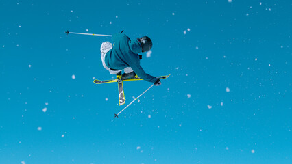 Action shot of a male skier jumping off a kicker and doing a high-flying trick.