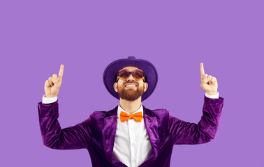 Cool cheerful man in funny glamorous outfit shows up on copy space on purple background. Man in...