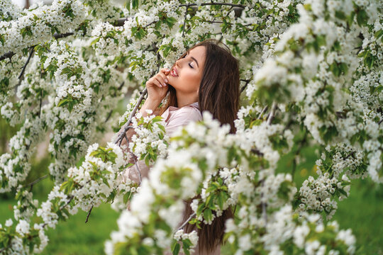 profile photo of a girl with long dark hair against the backdrop of a blooming garden