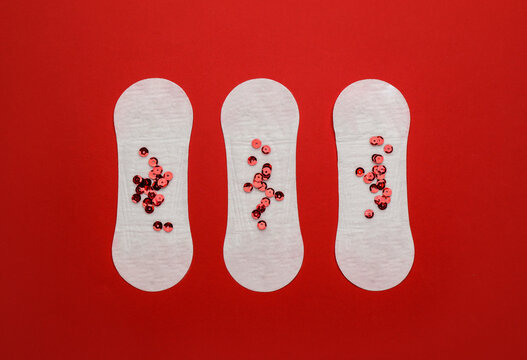 Sanitary pads with sequins on red background, flat lay. Menstrual cycle