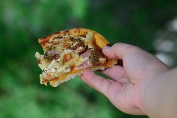 hand holding a pices of pizza 