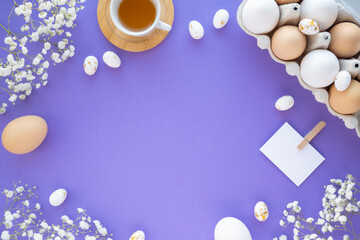 Spring Easter time. Flat lay of eggs with a frame of flowers. Flat lay, purple background