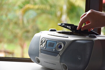 House owner is turning on the cd player which is on the balcony near the glass window to listen to the music at home, Soft and selective focus on cd player.