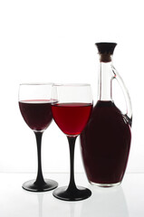 Two glasses with red wine and a bottle on a white background.