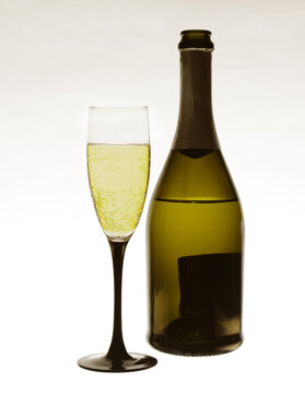 A glass of champagne and a bottle on a light background. 