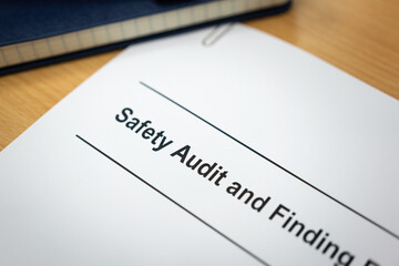 Safety audit and finding record document folder which is placed on wooden desk surface. Industrial...
