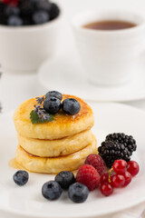 Blurred image of cheesecakes with different berries in a white plate on the table.