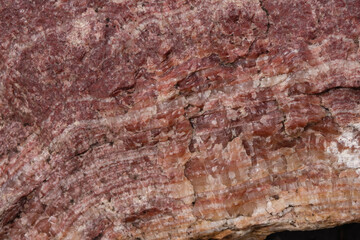 The texture of a red mineral. Gneiss rock. Layers. Stone mining. Selective focus.