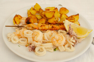 The dish of Fritto con spiedino e patate - potatoes and seafood fried with lemon