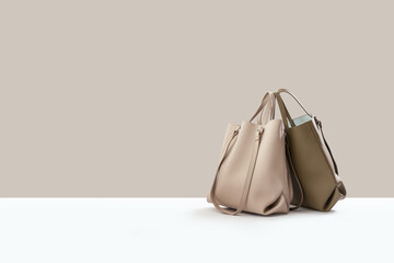 Beautiful beige leather female fashion bag isolated on light beige background, perspective view