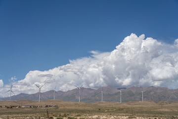 Some wind power facilities in the desert under blue sky and white clouds