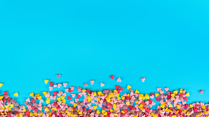 flatlay mockup made of multi-colored sugar hearts on a turquoise background in the the shape of the strip at the bottom of the frame