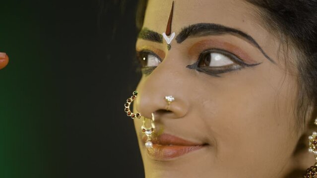 Close up shot of bharatanatyam dancer doing eye moments or drishti bheda by looking at camera - concept of indian culture, traditional classical dancer.