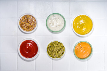 Assortment of different classic sauces and dips in sauceboats. Mayonnaise, ketchup, tartare, mustard, pesto, sour cream, barbecue sauces with spices, herbs, lemon