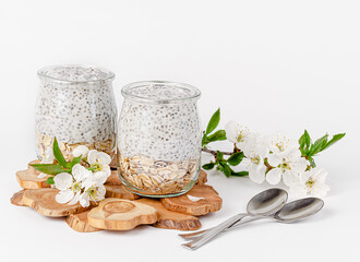 Chia seed pudding with yogurt and oats on white background decorated with flowers. Superfood concept. Copy space