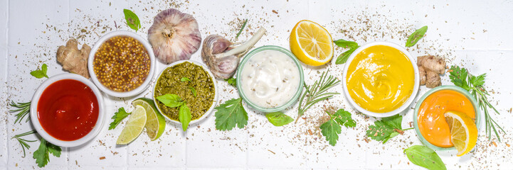 Assortment of different classic sauces and dips in sauceboats. Mayonnaise, ketchup, tartare, mustard, pesto, sour cream, barbecue sauces with spices, herbs, lemon
