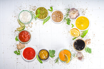 Assortment of different classic sauces and dips in sauceboats. Mayonnaise, ketchup, tartare, mustard, pesto, sour cream, barbecue sauces with spices, herbs, lemon