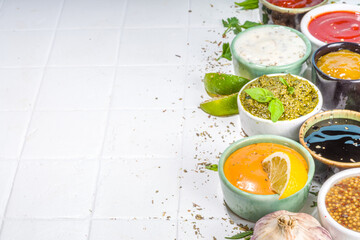 Assortment of different classic sauces and dips in sauceboats. Mayonnaise, ketchup, tartare, mustard, pesto, sour cream, barbecue sauces with spices, herbs, lemon