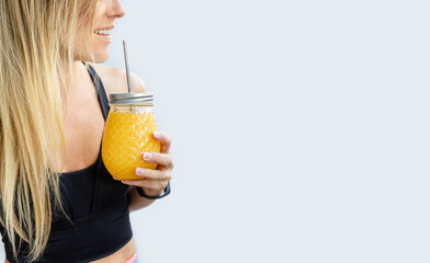 Cropped portrait of blonde smiling woman holding smoothie jar. Copy space.