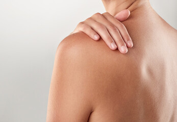 Whole body softness. Closeup studio shot of a woman touching her bare shoulder.