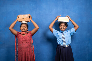 Two girl kids with books and bricks on each other head looking at camera - concept poverty and...