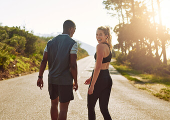 My guy makes the best workout buddy. Shot of a fit young couple slowing down for a walk during...
