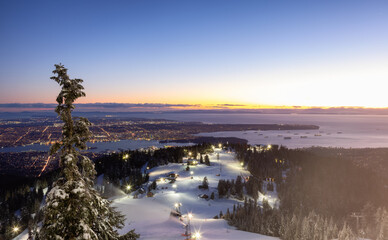 View of Top of Grouse Mountain Ski Resort with the City in the background. North Vancouver, British Columbia, Canada. Sunset Sky
