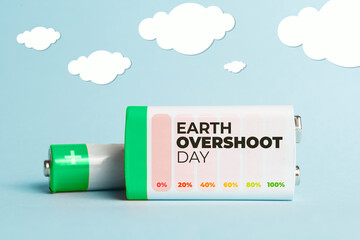 Earth overshoot day concept: batteries on a pastel blue background with some painted clouds