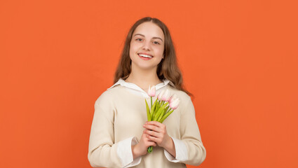 happy teen girl with tulip flowers on orange background, womens day