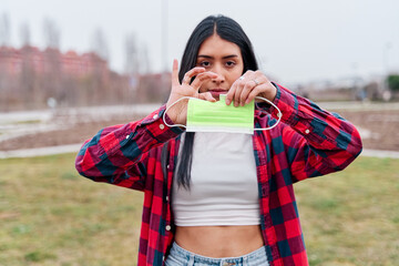 latina woman breaking an anti covid mask 19. concept of Pandemic End