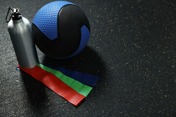 Blue medicine ball, bottle and elastic bands on floor, space for text