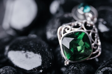 Emerald earring on black stones under the sun
