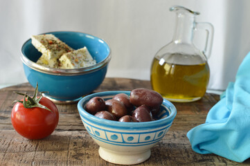 Greek kalamata olives in the blue bowl with other fresh ingredients, feta cheese, olive oil, tomatoes