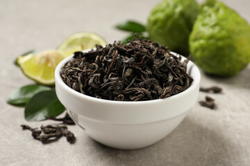 Dry bergamot tea leaves and fresh fruits on light grey table, closeup