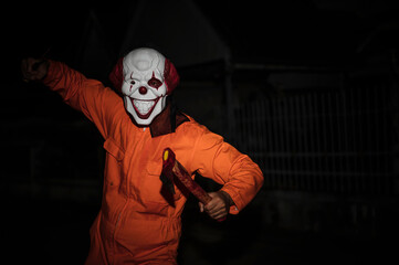 Asian handsome man wear clown mask with weapon at the night scene,Halloween festival concept,Horror...