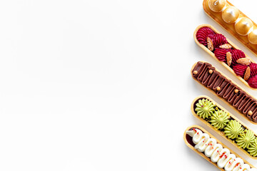 A lot of french dessert eclairs with colorful topping
