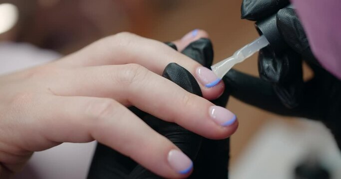 Manicurist applies gel lacquer to the nails of the client at beaty salon, cosmetology and beauty business, 4k Prores 60p
