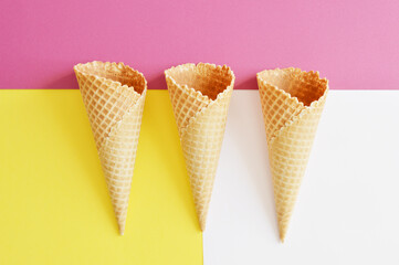 three waffle cones on a raspberry, yellow, white background