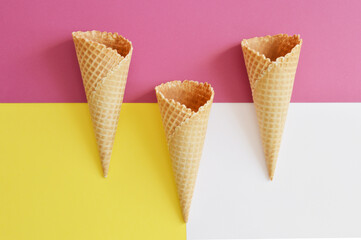 three waffle cones on a raspberry, yellow, white background