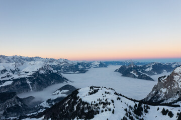 Fototapeta na wymiar Amazing sunrise with red sky and a beautiful landscape in the wonderful region in Switzerland called Mythenregion. Beautiful mountain called Mythen and an epic sea of fog in the background.