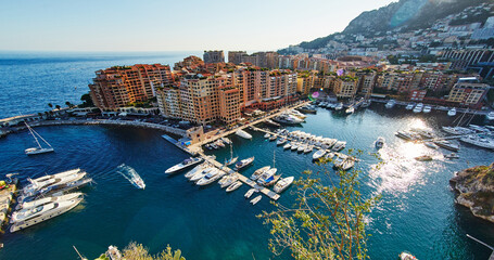 Panoramic image of Port Fontvieille - Monaco, top view from Monaco Ville, azur water, sun reflections on the water, harbour at sunny day, luxury apartments, a lot of yachts and boats, mountain