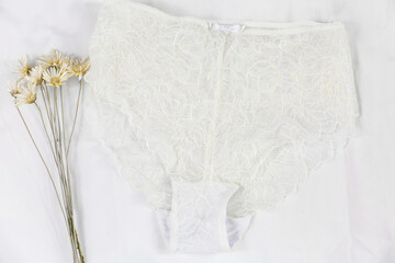 White women lace underlace and flowers on the bed. Top view, flat lay	