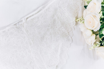 White women lace underlace and flowers on the bed. Top view, flat lay	