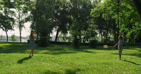 Couple siblings play badminton rackets chatting on green park. Summer picnic