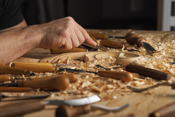 Wood carving, master's hands work with a wooden surface, a professional does wood crafts