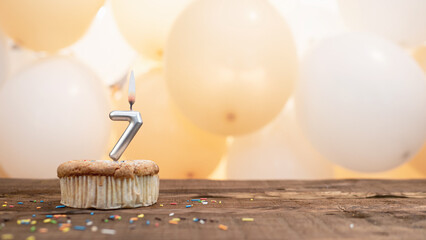 Happy birthday card with candle number 7 in a cupcake against the background of balloons. Copy...
